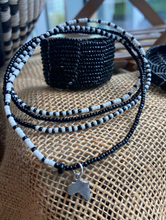 Load image into Gallery viewer, Black and white beaded bracelet / necklace with an Africa charm on a textured surface