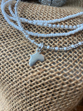 Load image into Gallery viewer, Necklace with a small pendant of Africa on a textured surface