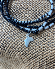 Load image into Gallery viewer, Black, white, and gray beaded bracelet with a silver Africa charm on a textured fabric background