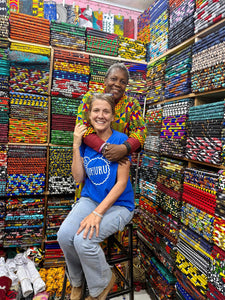 Two people in a room filled with kitenge fabric rolls.